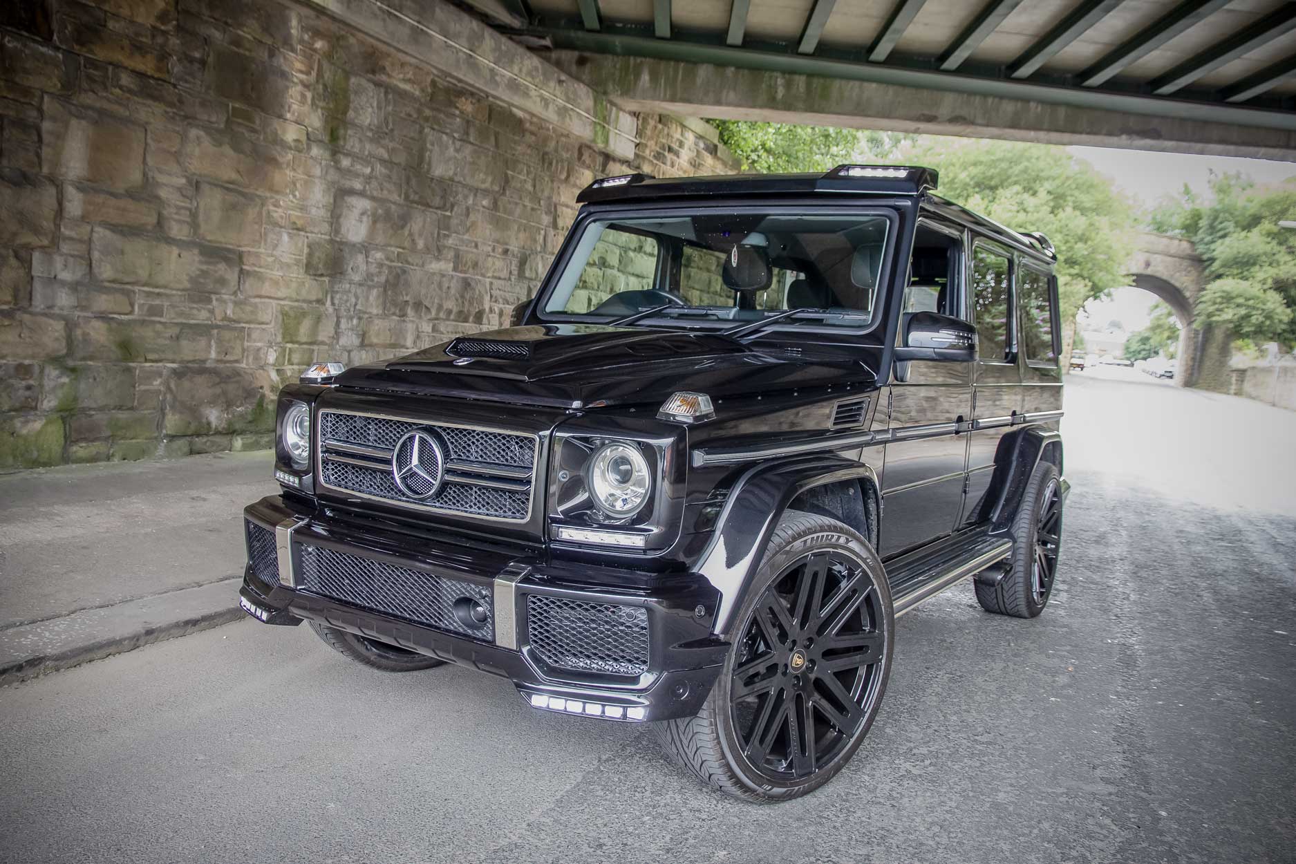 Front quarter view of a Mercedes G Wagon W463 Gen 1 1990-2017. Shot inside a tunnel. Fitted with Barugzai EXEL 24” alloy wheels, in Gloss Black.