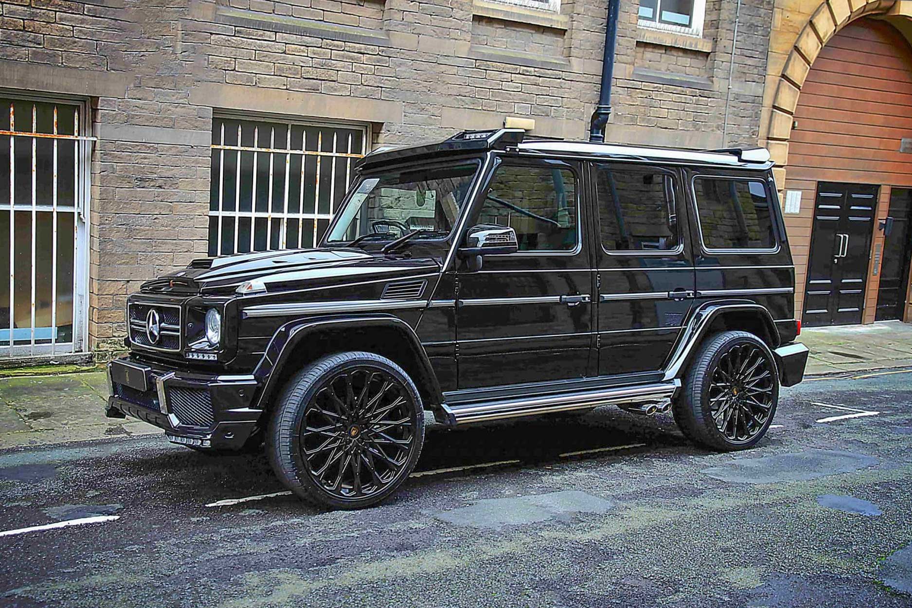 Front quarter view of a Black Mercedes G Wagon W463 Gen I 1990-2017. Shot outside a city street. Fitted with Barugzai Majestic 24” alloy wheels, in Gloss Black.