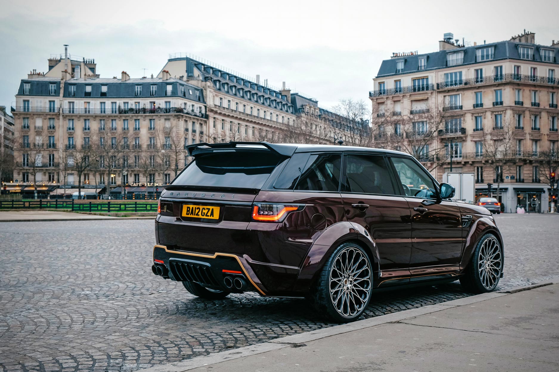 Rear quarter view of a Brown Range Rover Sport L494 2018-2022. Shot outside Paris high street. Fitted with Barugzai Majestic 24” alloy wheels, in Gloss Black Polished Face.