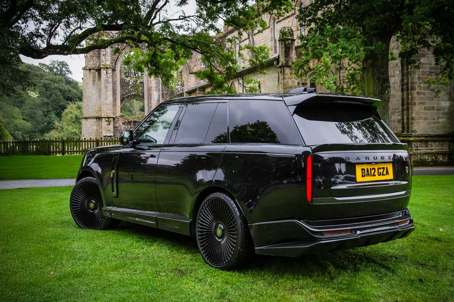 Rear quarter view of a Black Range Rover L460 2022+. Shot outside an old Abbey. Fitted with Barugzai Vortex Forged 24” alloy wheels, in Gloss Black Polished Face.