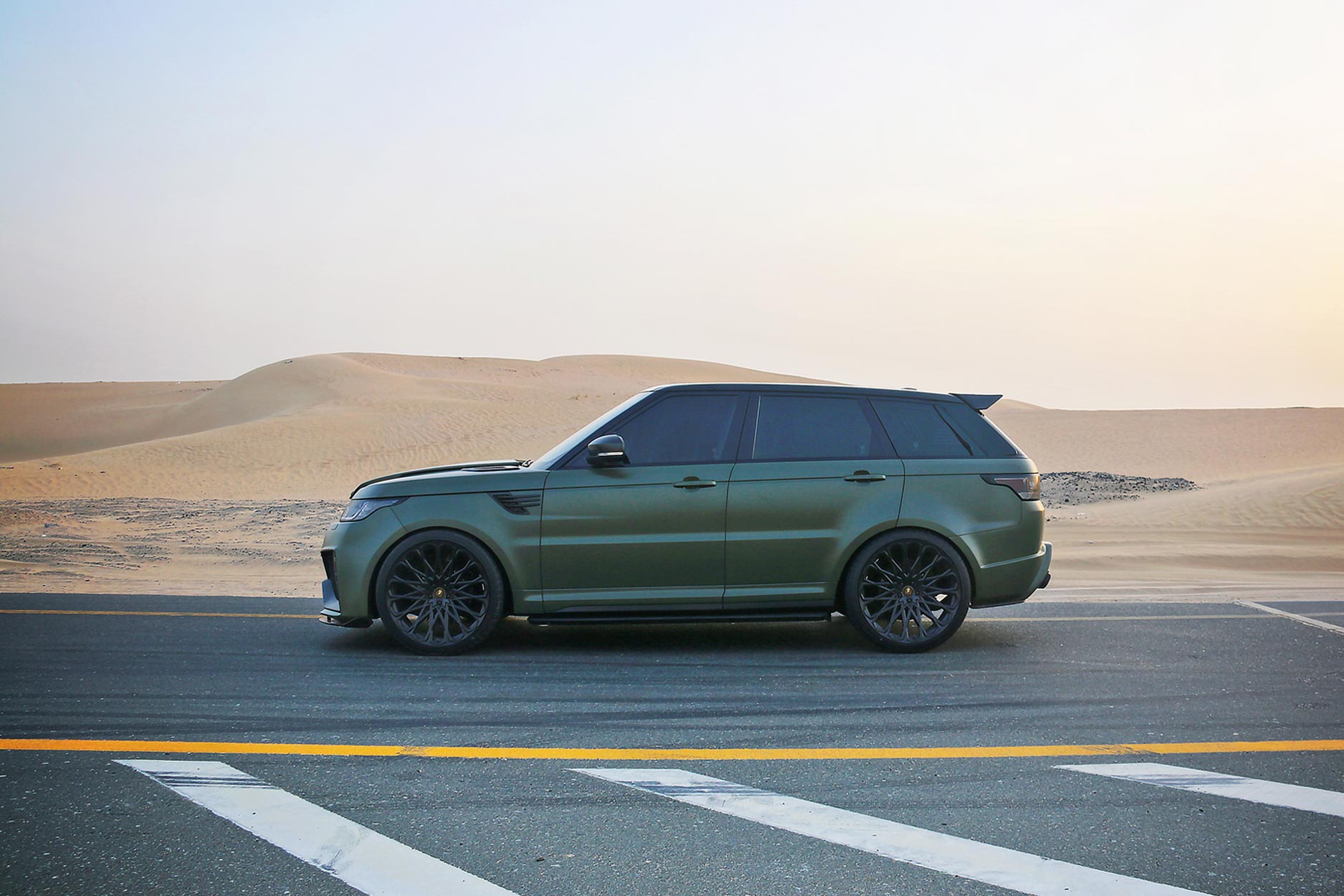 Side view of a Military Green Range Rover Sport L494 2013-2017. Shot outside a desert. Fitted with Barugzai Majestic 24” alloy wheels, in Gloss Black.