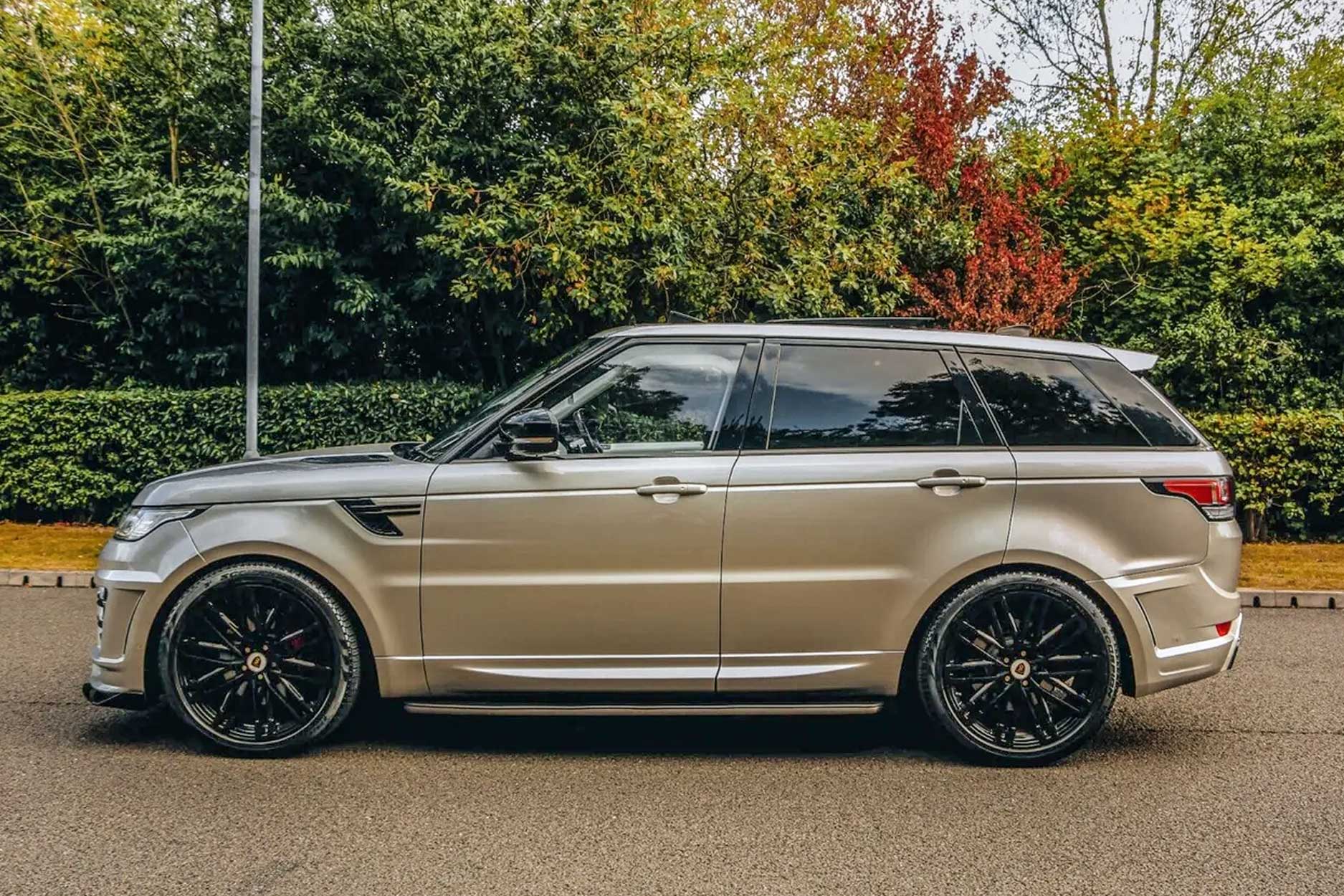 Side view of a Champagne Range Rover Sport L494 2013-2017. Shot outside with a scenic setting. Fitted with Barugzai Dawn 22” alloy wheels, in Gloss Black.