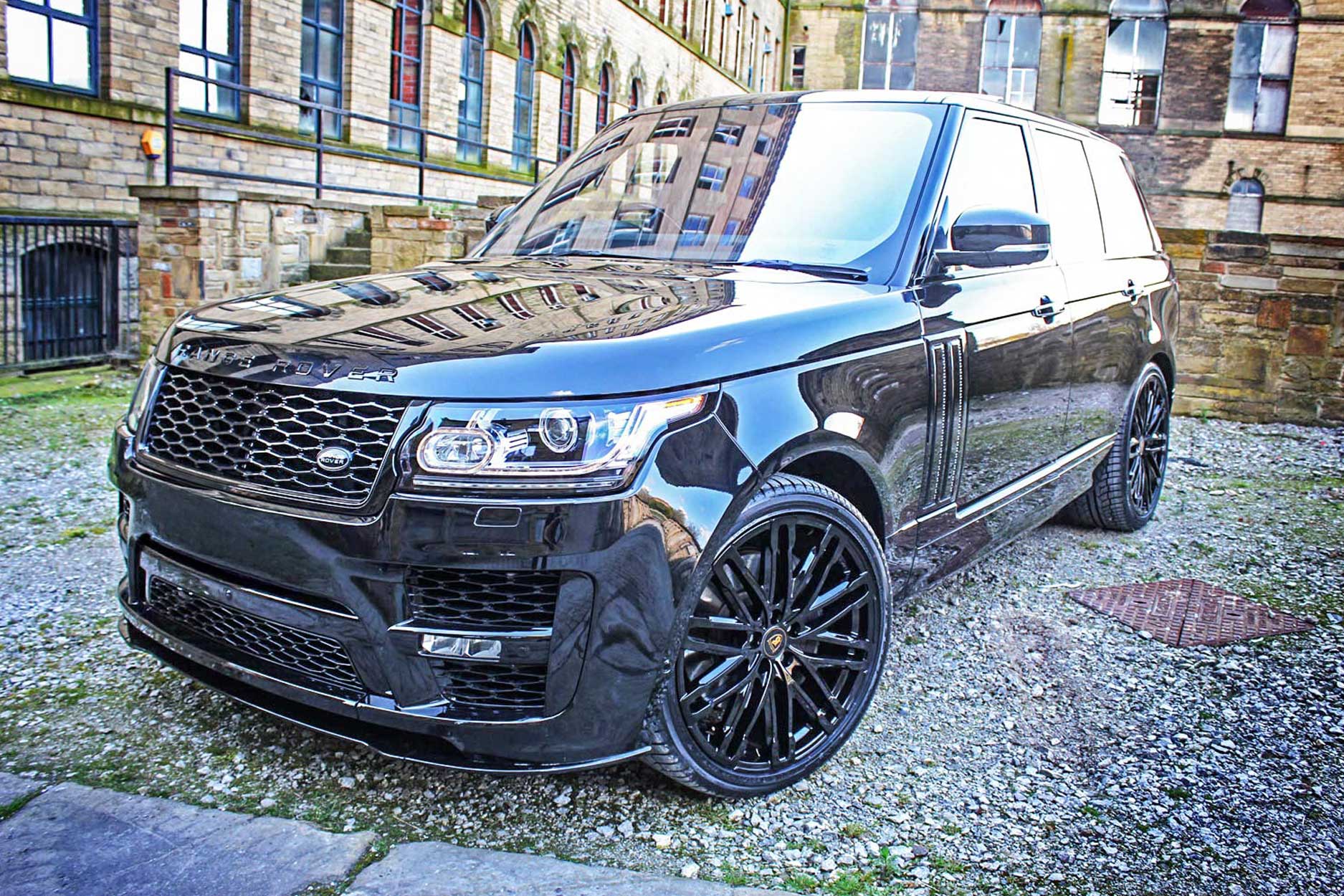 Front quarter view of a Black Range Rover L405 2013-2017. Shot outside an old mill. Fitted with Barugzai Dawn 22” alloy wheels, in Gloss Black.