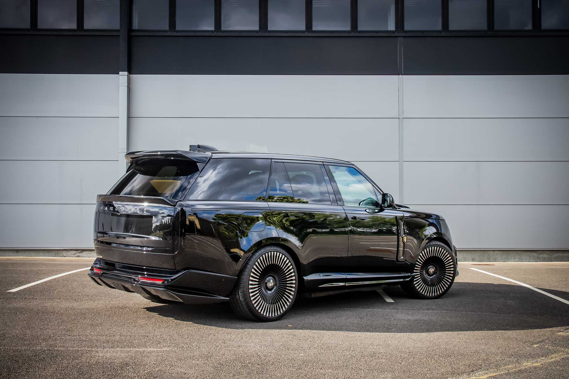 Rear quarter view of a Black Range Rover L460 2022+ with a Scoop fitted. Parked on a road with a grey backdrop. Fitted with Barugzai Vortex Forged 24” alloy wheels, in Gloss Black Polished Face.