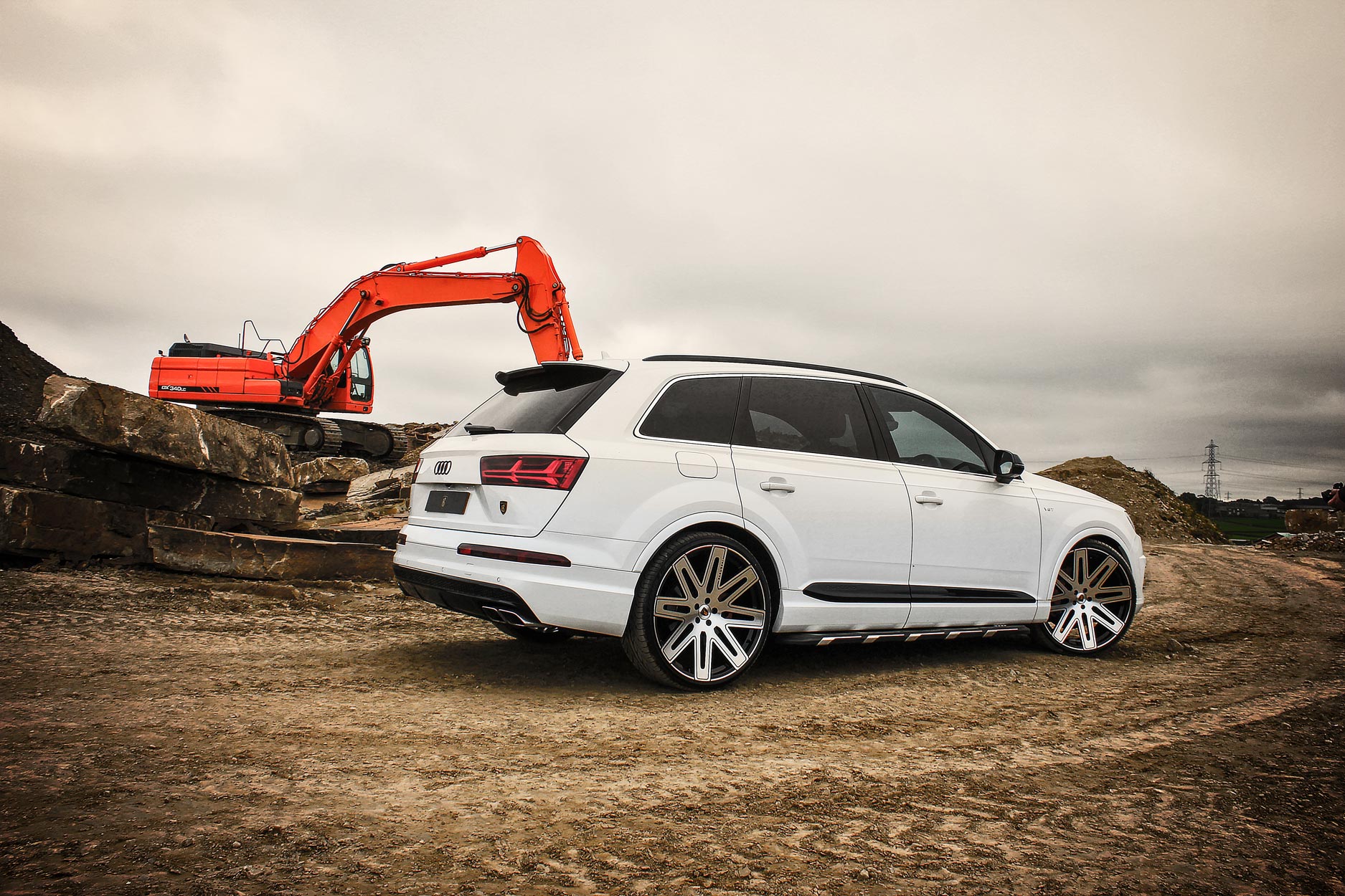 Rear quarter view of a White Audi Q7 2016+. Shot outside a quarry. Fitted with Barugzai EXEL 24” alloy wheels, in Gloss Black Polished Face.