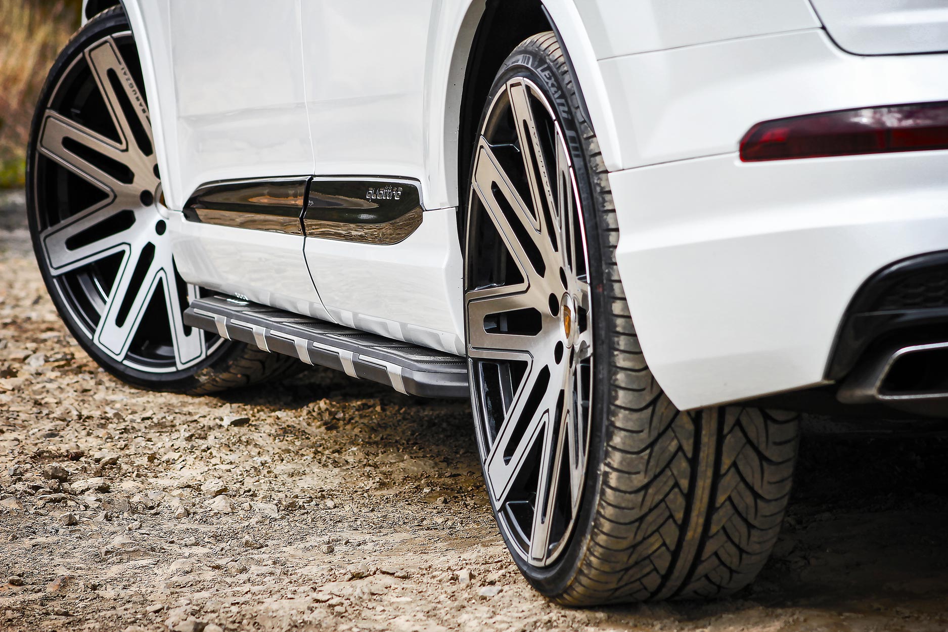 Side quarter detail view of a White Audi Q7 2016+. Shot outside a quarry. Fitted with Barugzai EXEL 24” alloy wheels, in Gloss Black Polished Face.
