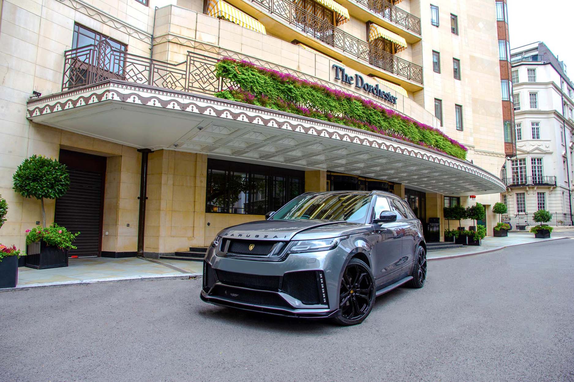 Front quarter view of a Barugzai Range Rover Velar 2017+ . Shot outside a city high street. Fitted with Barugzai Opium 22” alloy wheels, in Gloss Black