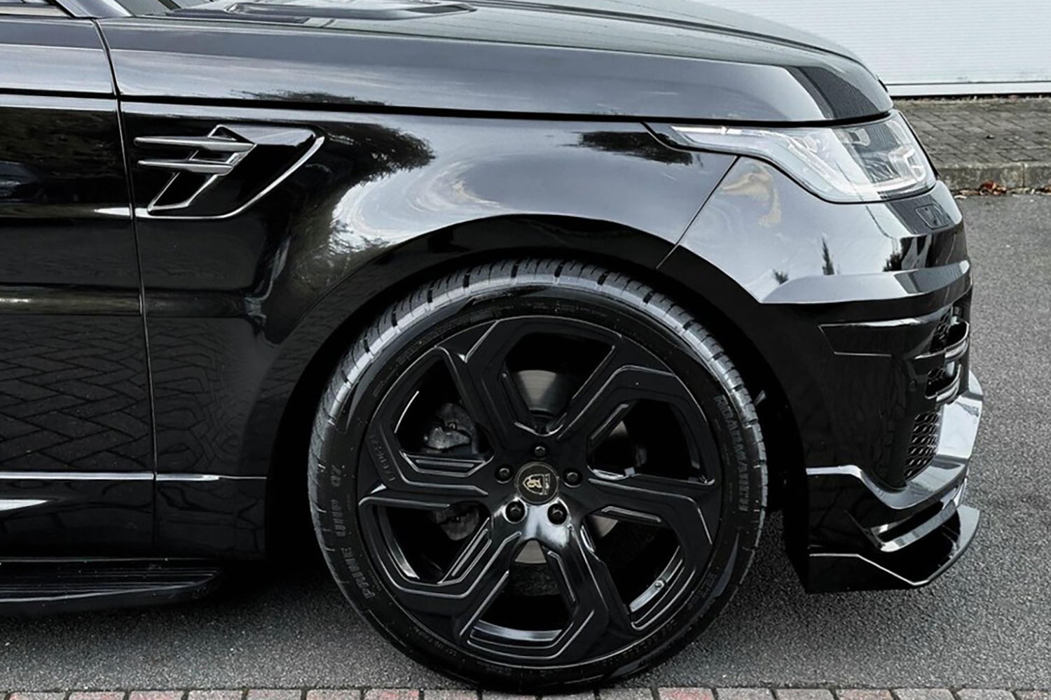 Side detail view of a Black Range Rover Sport L494 2018-2022. Shot outside a showroom. Fitted with Barugzai Sabre 22” alloy wheels, in Gloss Black.