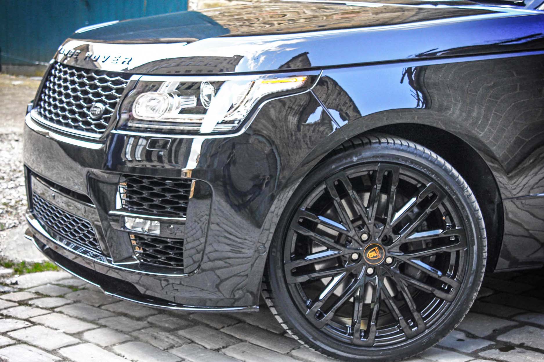Front quarter detail view of a Black Range Rover L405 2013-2017. Shot outside an old mill. Fitted with Barugzai Dawn 22” alloy wheels, in Gloss Black